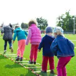 Children walking along a balance beam in the outdoor play area