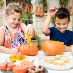 Children decorating pumpkins outdoors