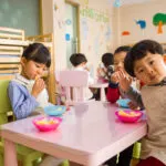 Children eating a snack together at a classroom table